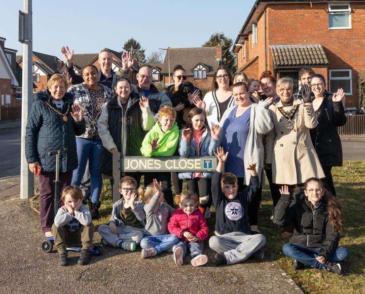 A large group of people stood in front of a road name, which is 'Jones Close'.